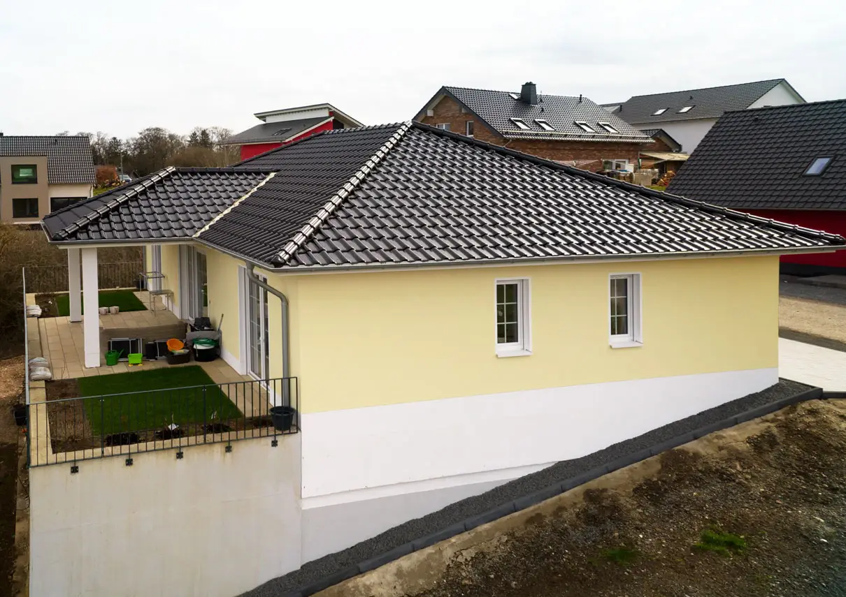 Hangseite des Bungalows mit erhöhter, überdachter Terrasse über dem Garten