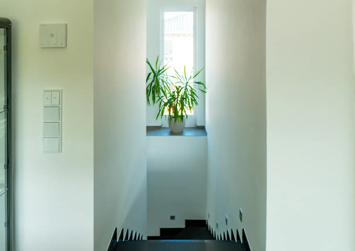 Treppe zur Obergeschosswohnung mit hohem, schmalem Fenster