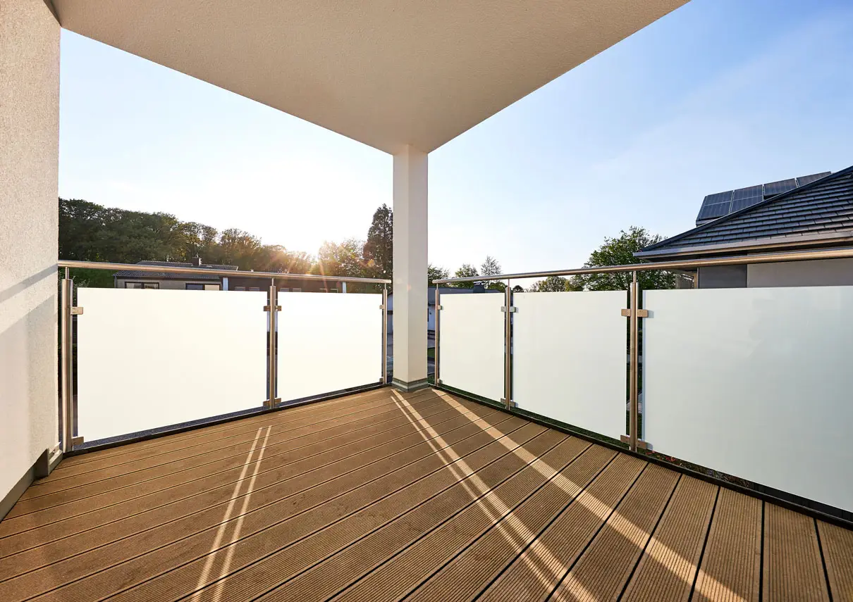 Loggia mit Glasbrüstung und Holzdielen in der Abendsonne