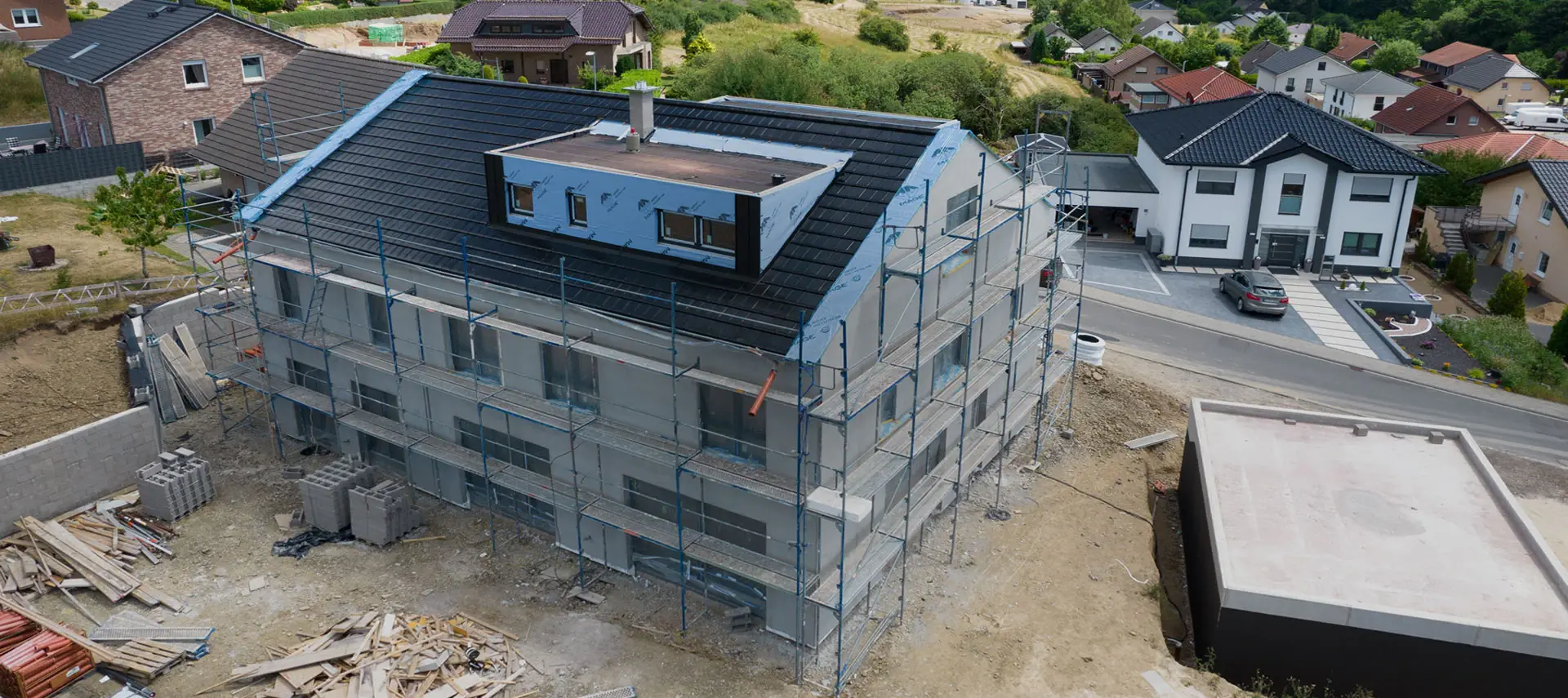 Luftbild von NF22 im Rohbau: Zweifamilienhaus mit Satteldach und Gaube in Hanglage