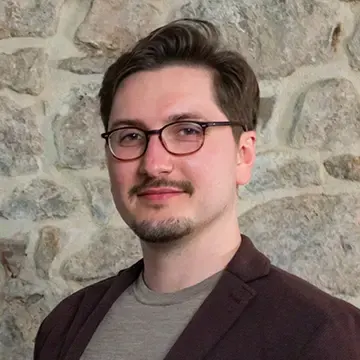 Porträt von M. Sc. Thomas Neufeld vor einer Natursteinwand