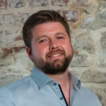Porträt von Dipl.-Ing. Waldemar Neufeld vor einer Natursteinwand