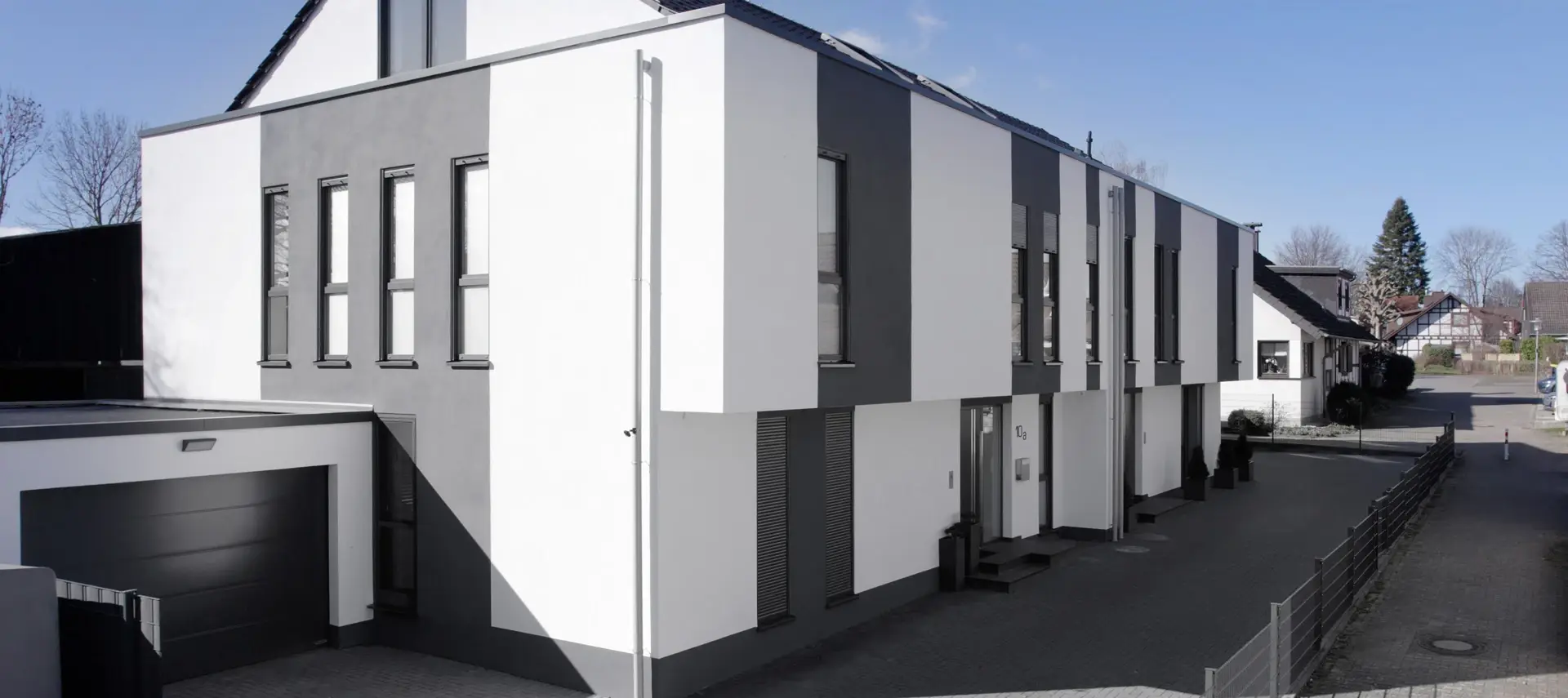 Doppelhaus ZW18 in Weiß und Anthrazit: Flachdachbau mit zurückgesetztem Satteldach und Attika